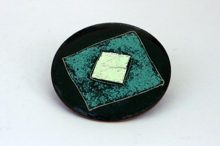 brooch with silver and turquoise squares on dark background